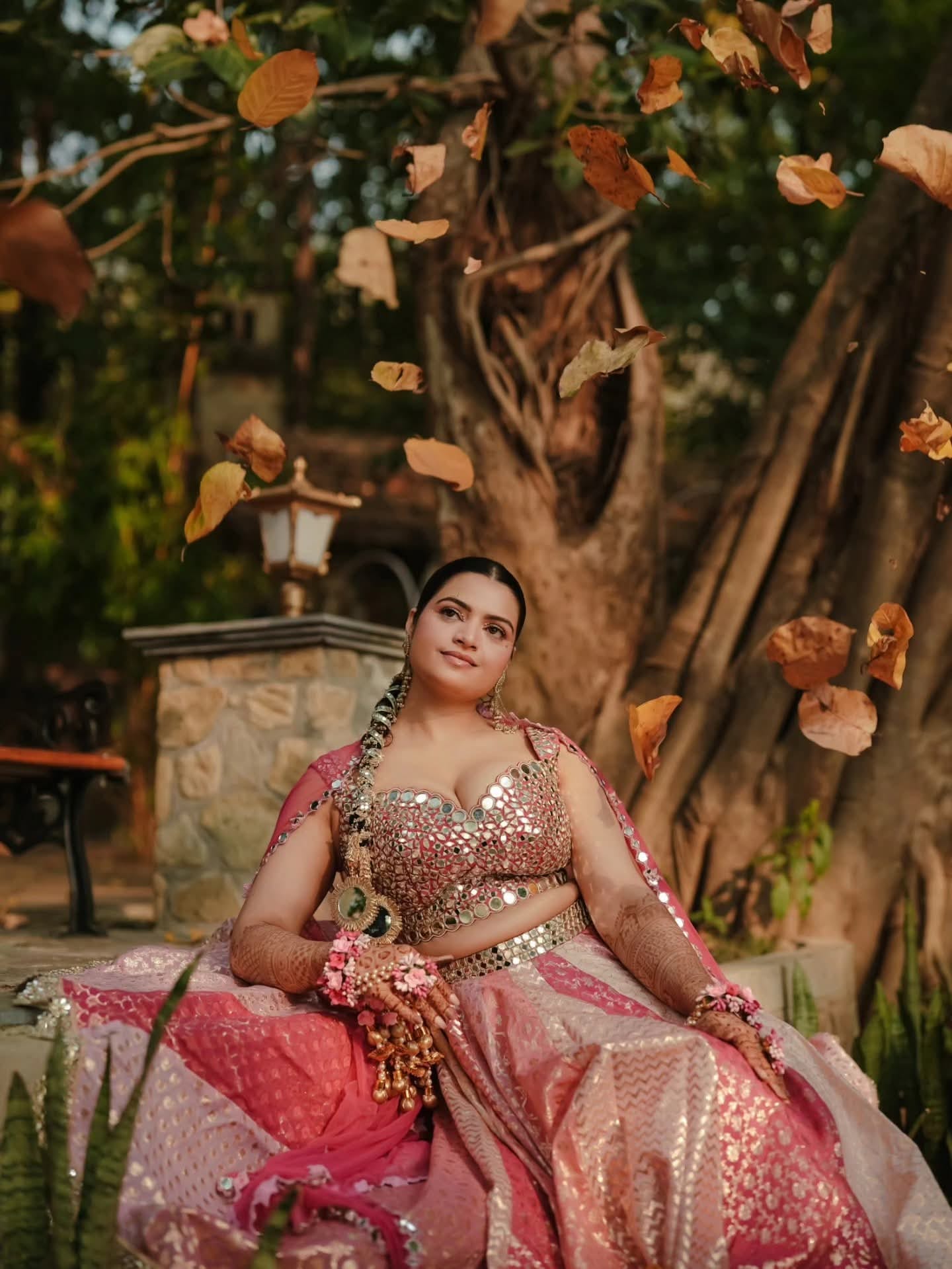 The bride in pink beneath a banyan tree as petals fall