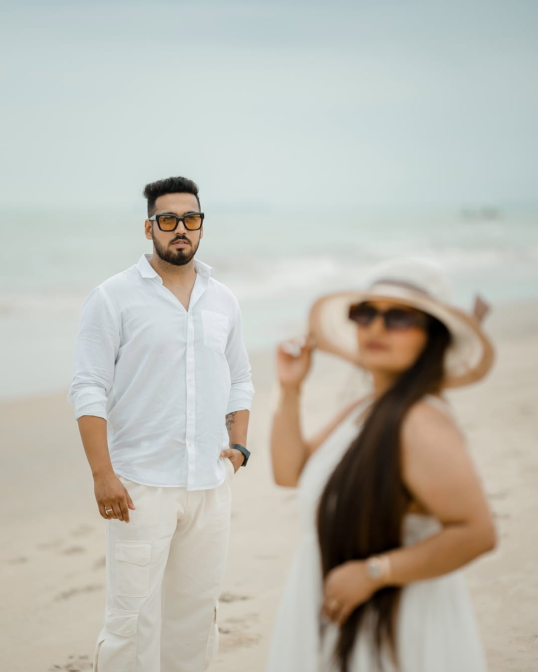 A couple dressed in white on a beach during a pre-wedding shoot