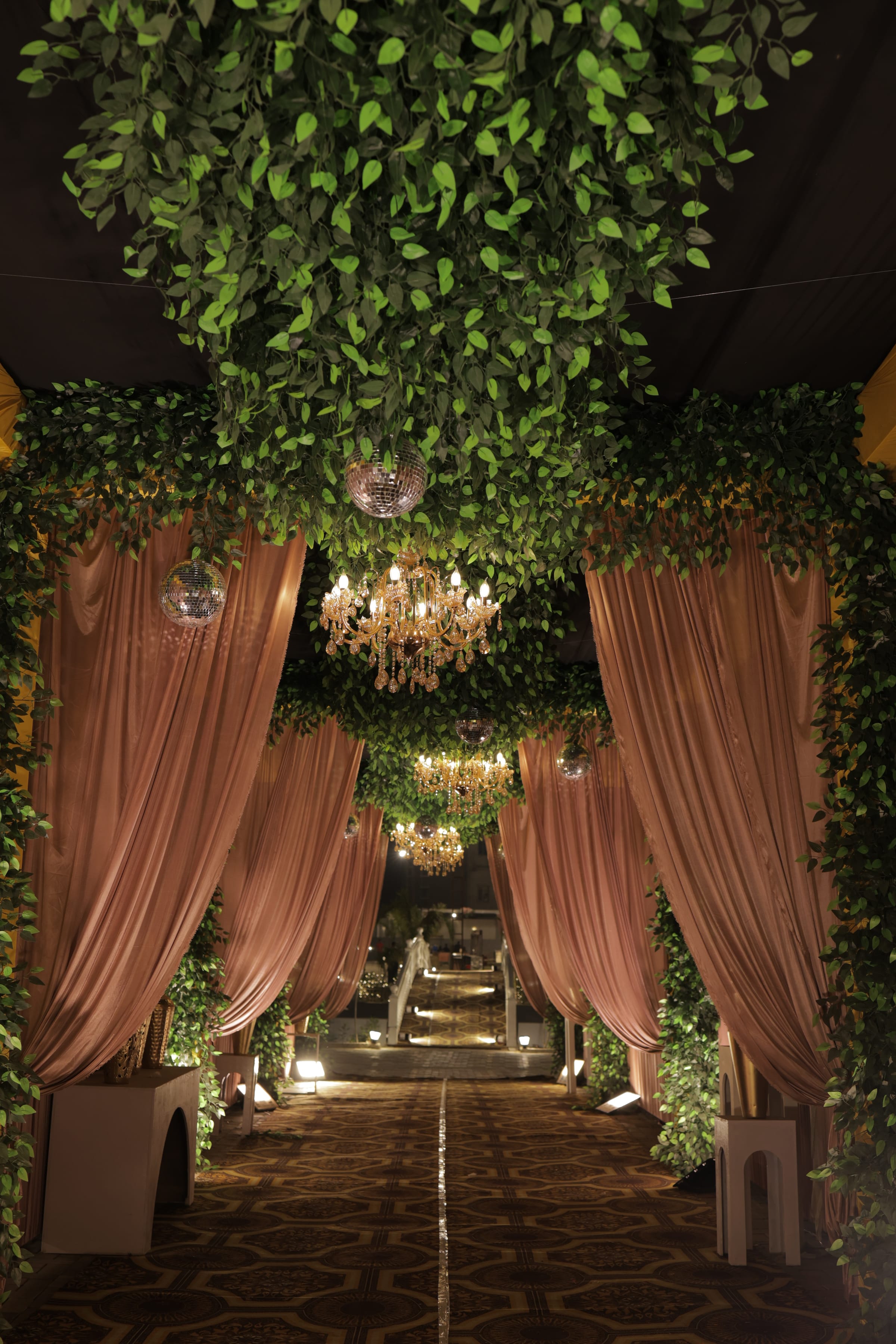 Draped fabric against a green foliage wall, hung with mirror balls