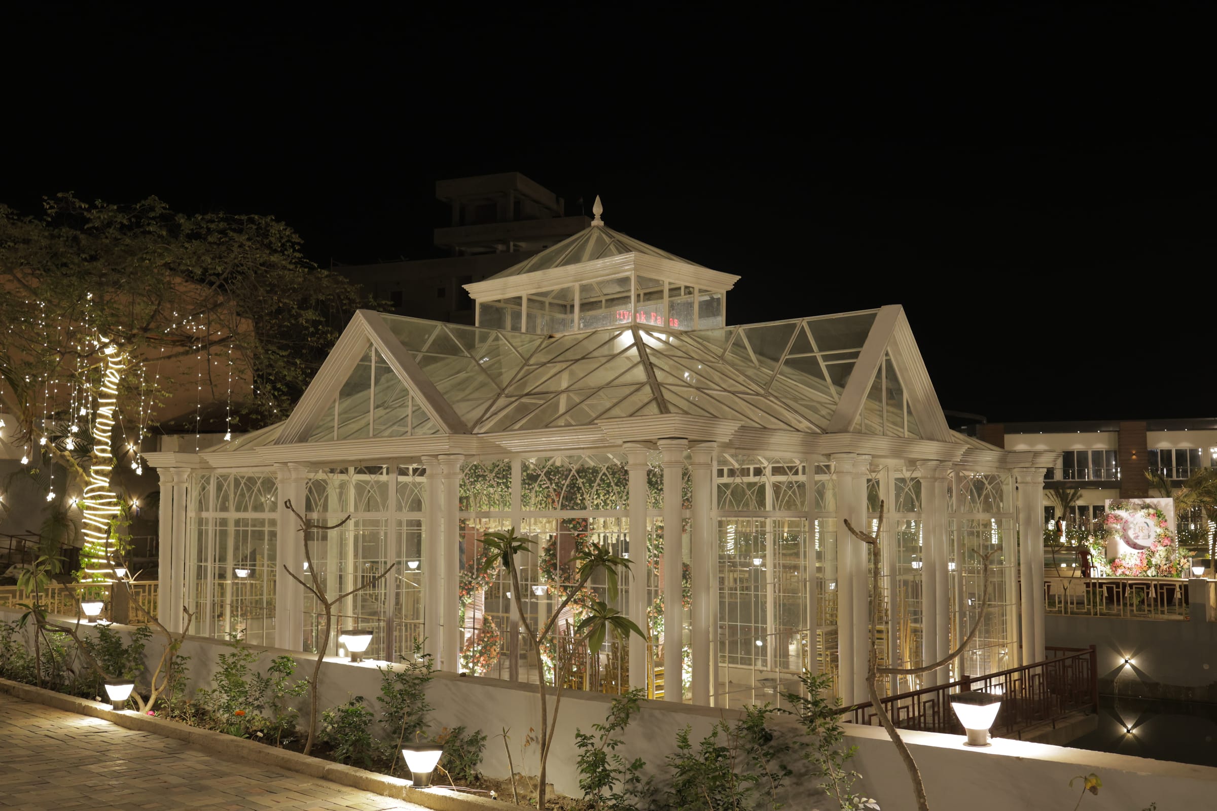 A lit glasshouse pavilion in the grounds after dark