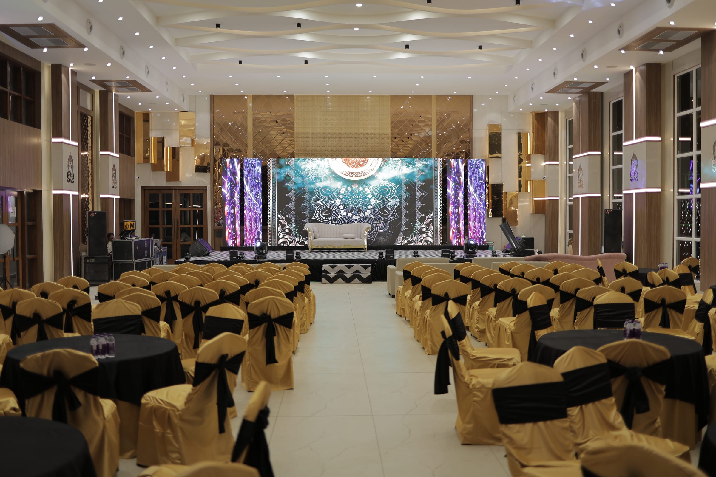 A banquet hall laid for dinner, chairs dressed in gold and black